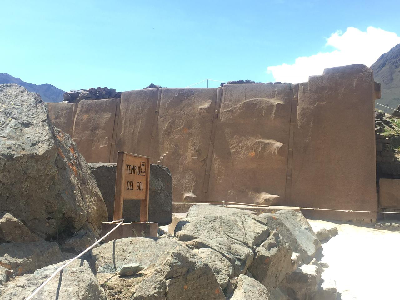 Calle empedrada del pueblo inca de Ollantaytambo con acequia de agua corriente y fortaleza al fondo, Valle Sagrado, Cusco, Perú